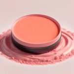 Picture of orange/coral coloured cream blush in a circular pot.